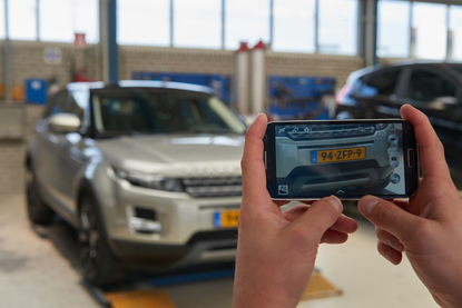 Fitter with a mobile phone scaning a license plate